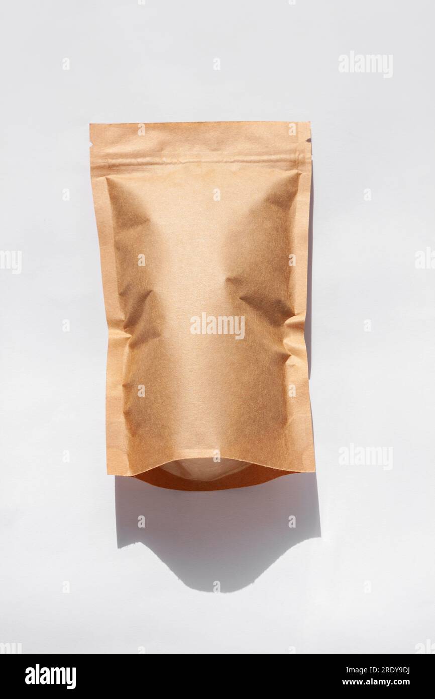 Brown kraft paper pouch bags with coffee beans top view with shadow isolated on white background. Packaging for foods and goods template mockup. Pack Stock Photo