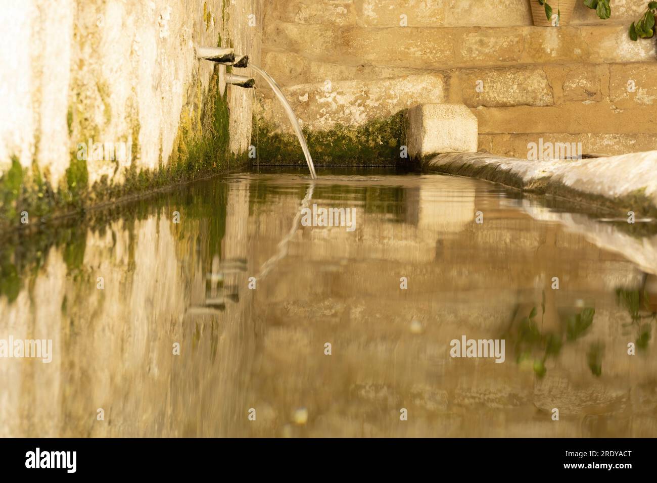Clear and crystalline water comes out of a public fountain in the town of Castellote, Teruel, Aragon, Spain, Maestrazgo, beautiful reflections in the Stock Photo