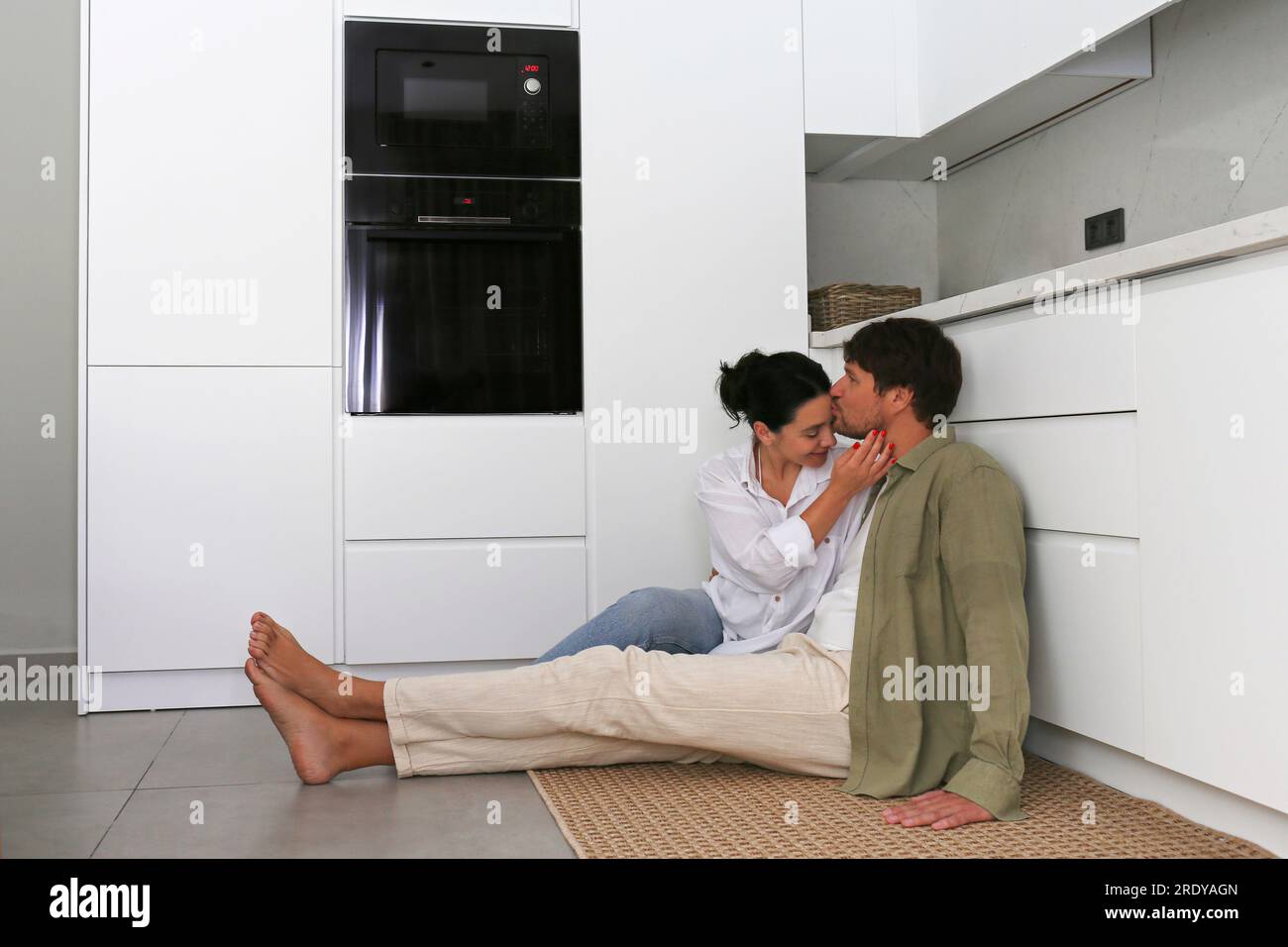 Man kissing woman sitting in kitchen at home Stock Photo