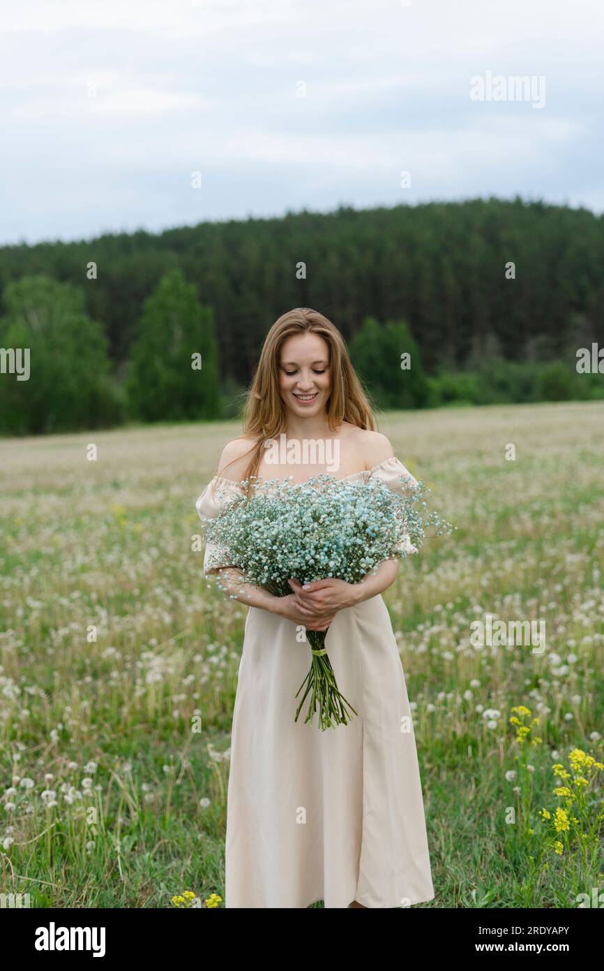 Smiling young woman holding flower bouquet on field Stock Photo