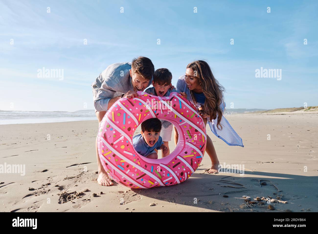 Playful family with doughnut shaped inflatable swim ring at beach Stock
