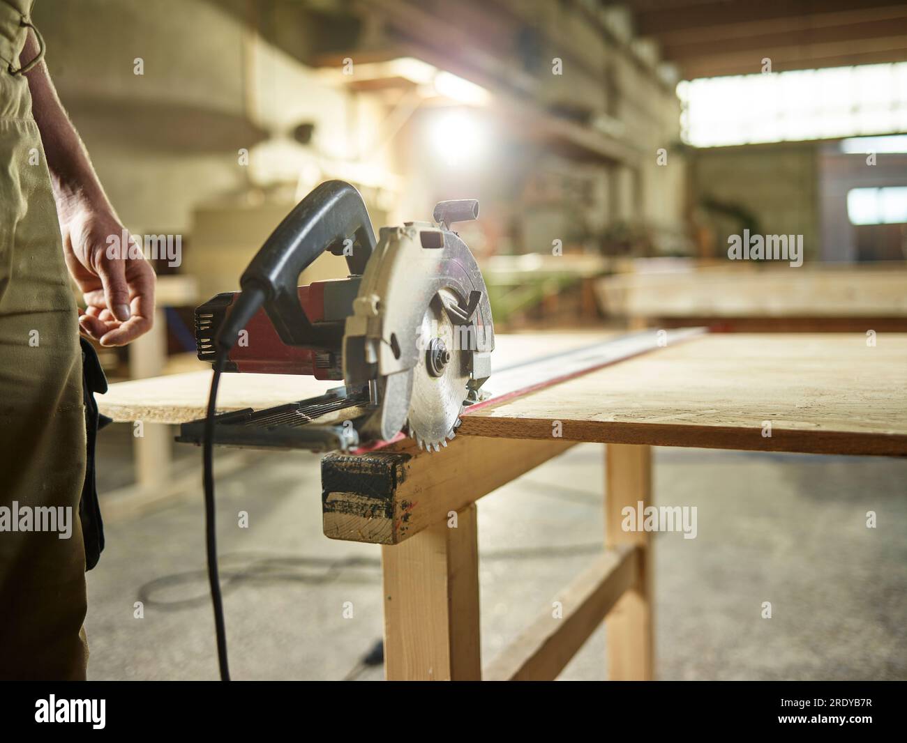 Carpenter with circular saw on oriented strand board in workshop Stock Photo