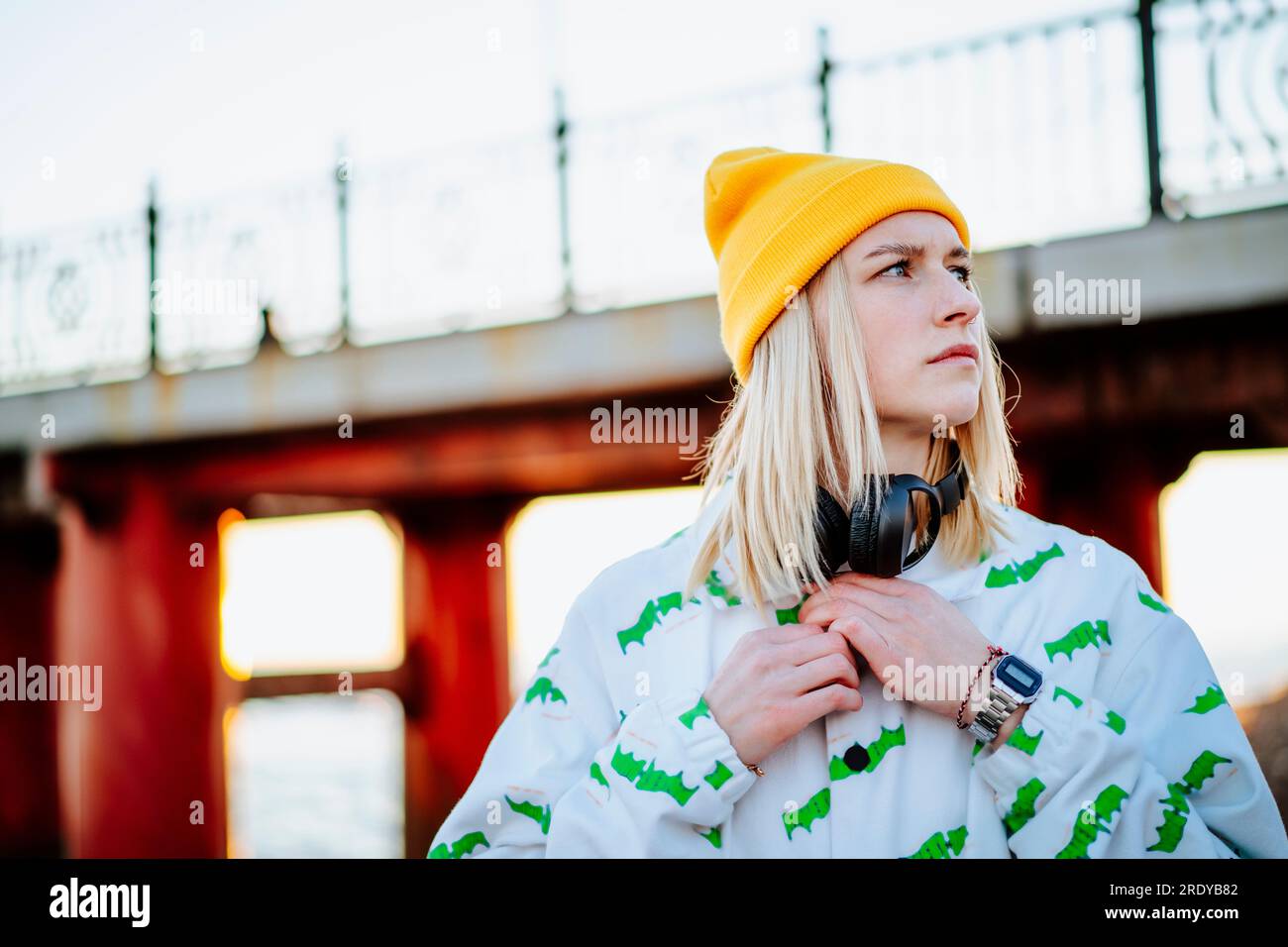 Blond young woman standing in front of bridge Stock Photo - Alamy