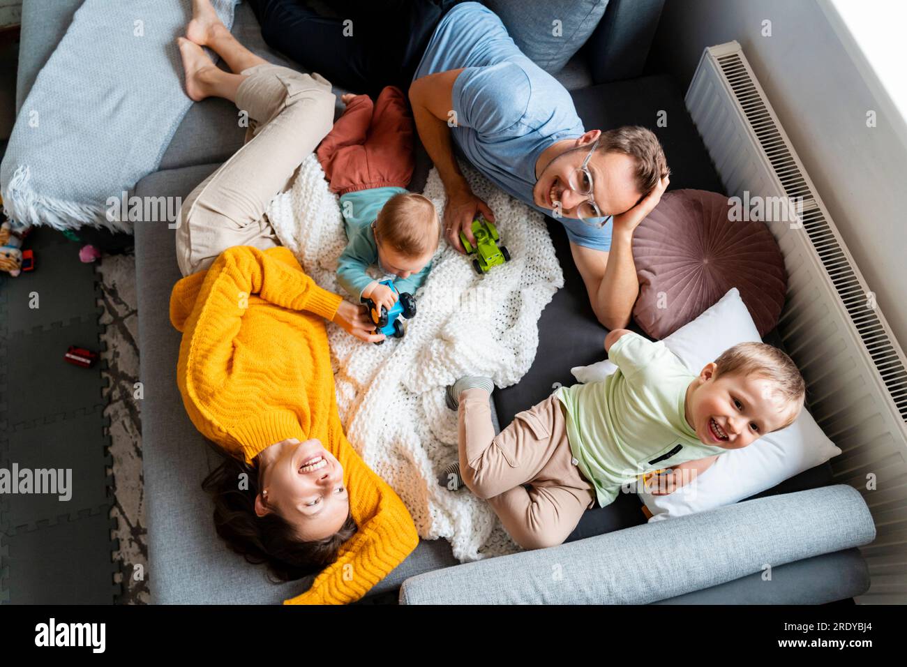 Parents spending leisure time with children playing on couch at home Stock Photo