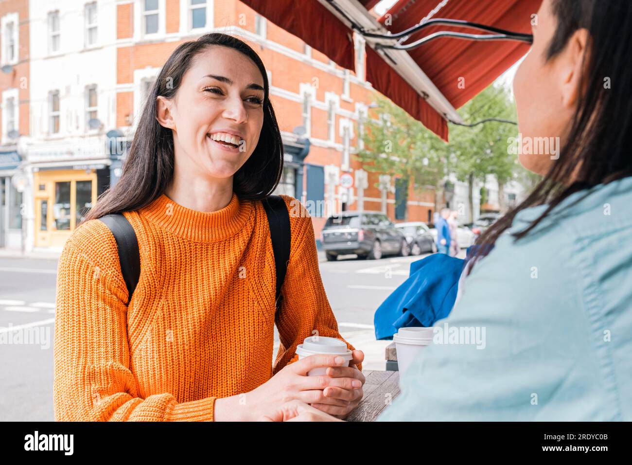 Smiling friends talking and drinking coffee at sidewalk cafe Stock Photo