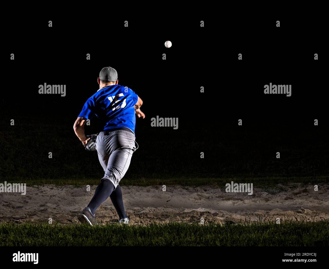Young man with sports clothing throwing baseball at night Stock Photo