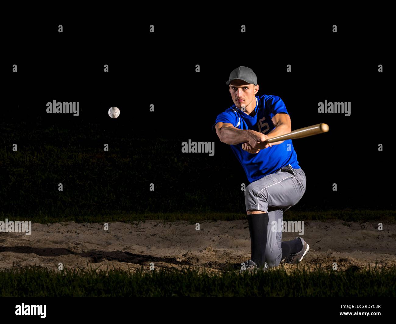 Young man hitting baseball with bat at night Stock Photo Alamy