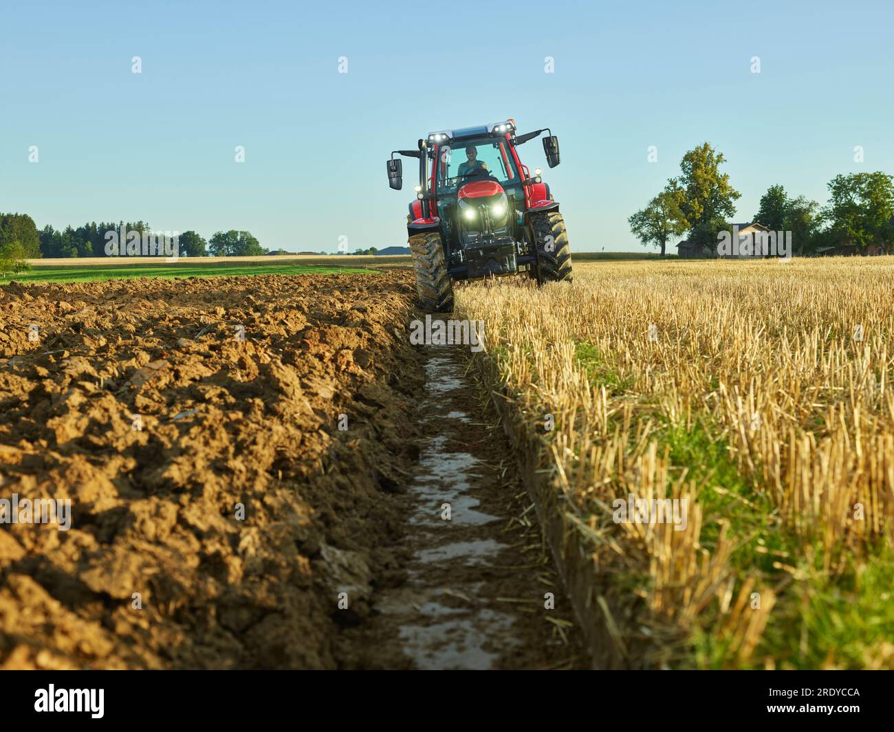 Farmer driving tractor amidst crops in farm Stock Photo - Alamy