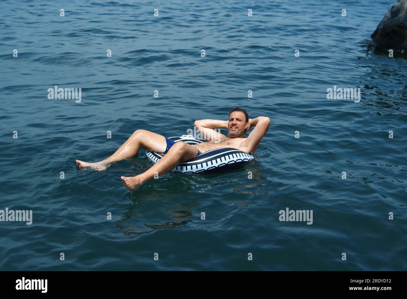 Middle-aged man on life buoy at sea Stock Photo