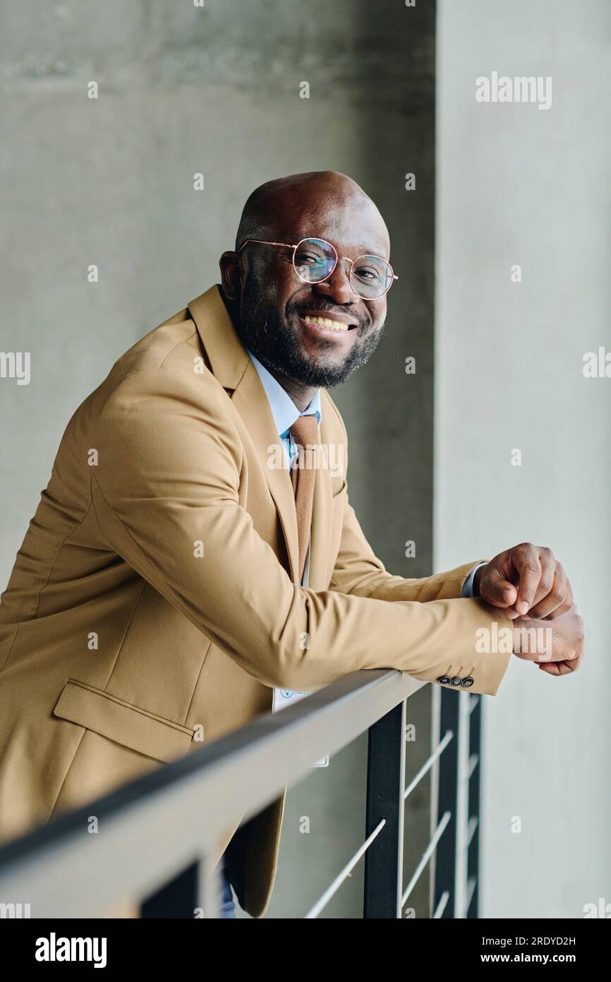 Smiling businessman in suit leaning on railing Stock Photo