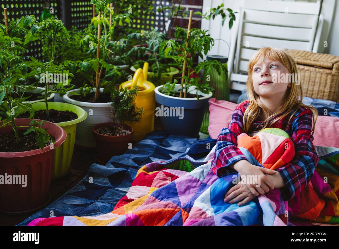 Thoughtful girl wrapped in blanket sitting in balcony Stock Photo - Alamy