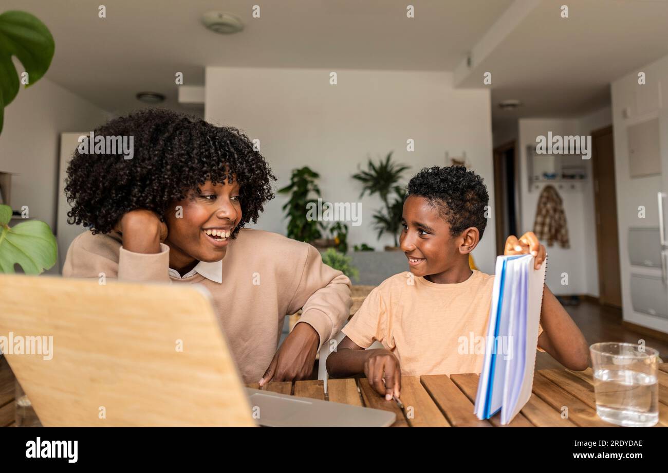 Happy son showing homework to mother at home Stock Photo
