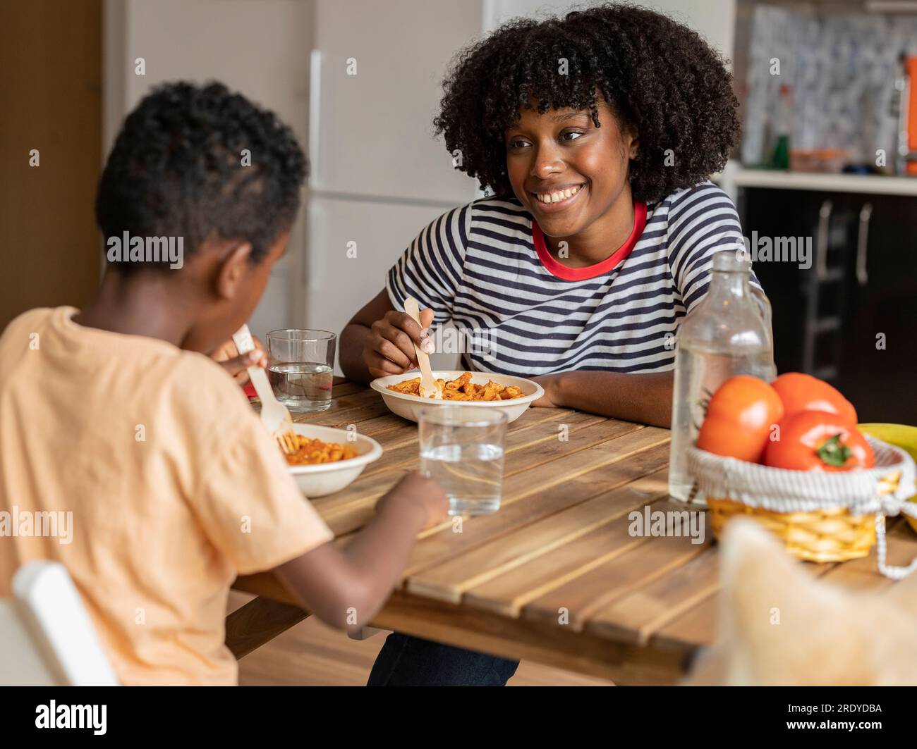 Smiling mother and son having meal together at home Stock Photo