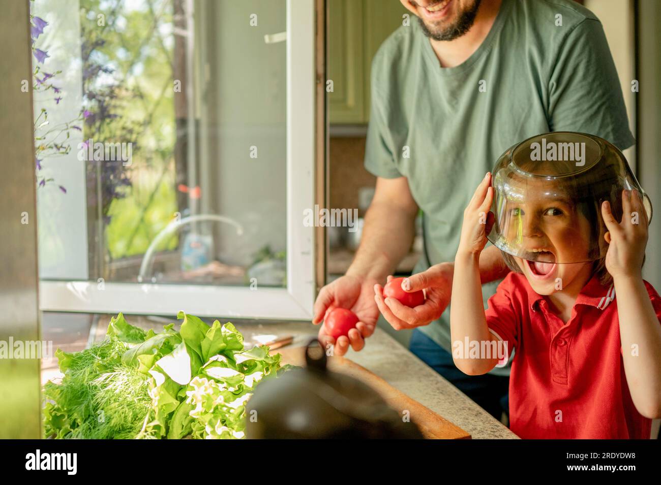Playful boy covering face with bowl by father at home Stock Photo - Alamy