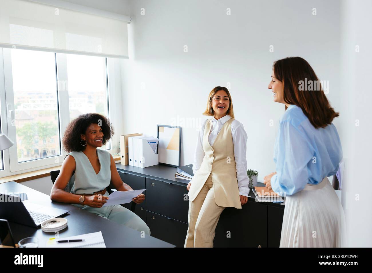 Happy multiracial colleagues discussing in office Stock Photo - Alamy