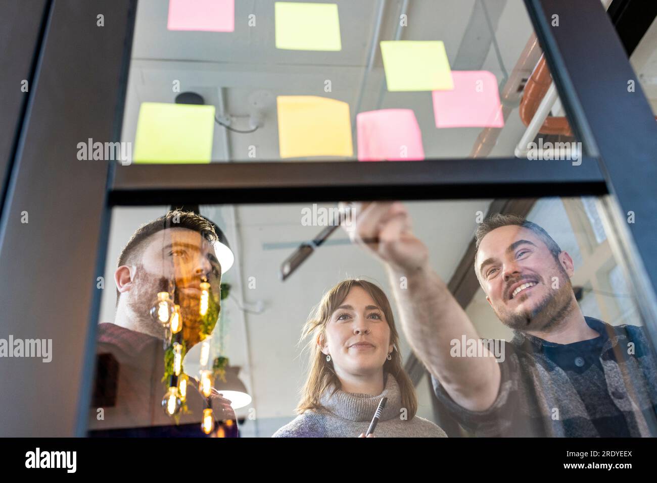 Happy businessman with colleagues discussing over adhesive notes Stock Photo