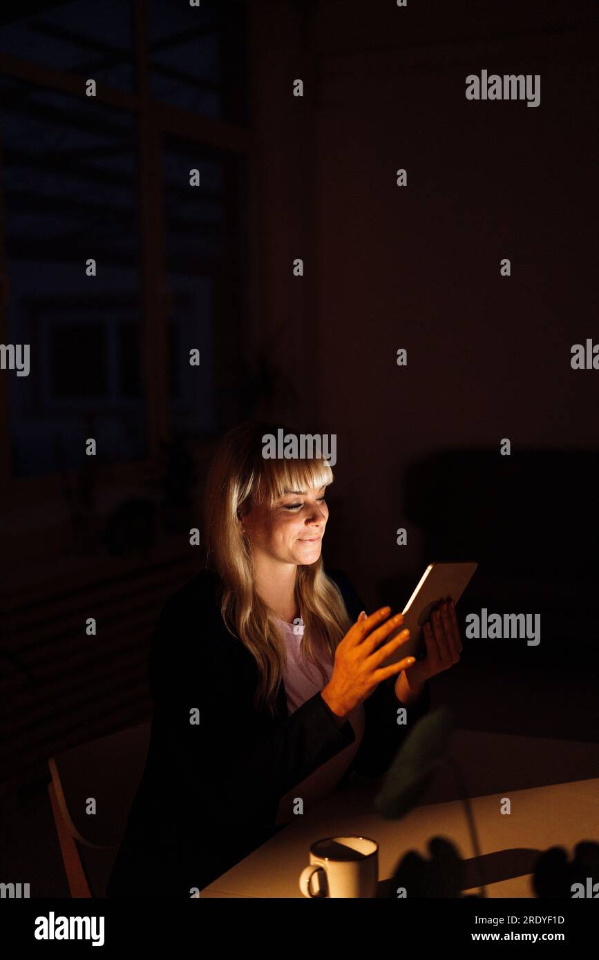 Blond woman using tablet PC at night Stock Photo