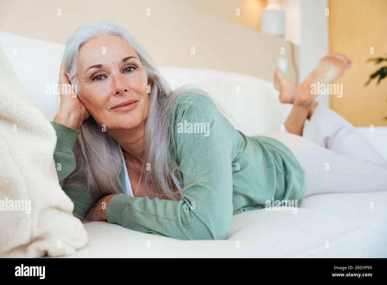 Smiling mature woman relaxing on sofa at home Stock Photo - Alamy