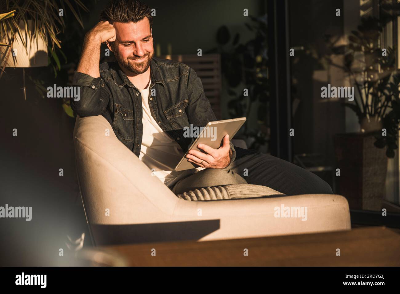 Smiling man using tablet PC at home Stock Photo