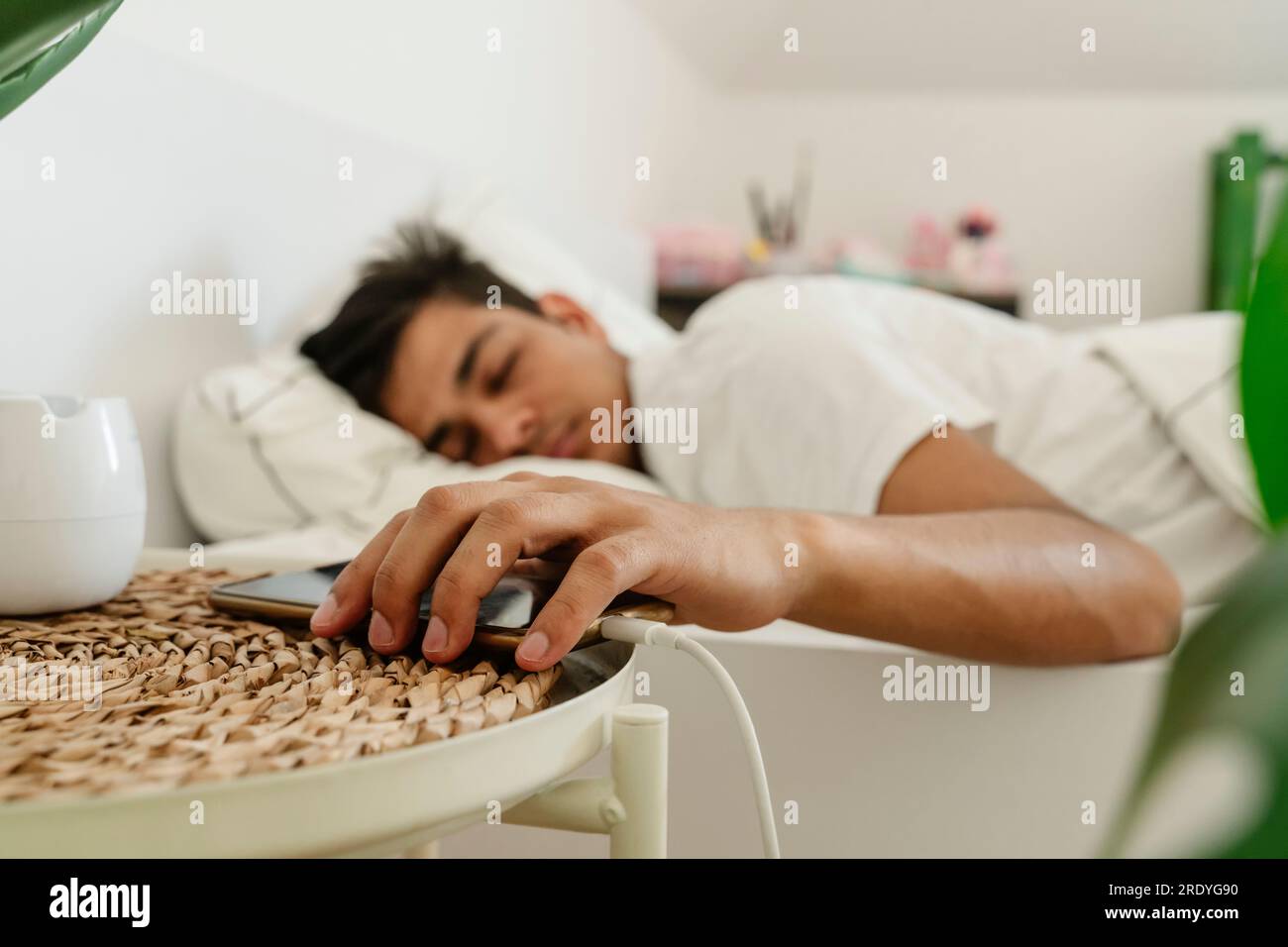 Tired man keeping smart phone on side table near bed Stock Photo Alamy