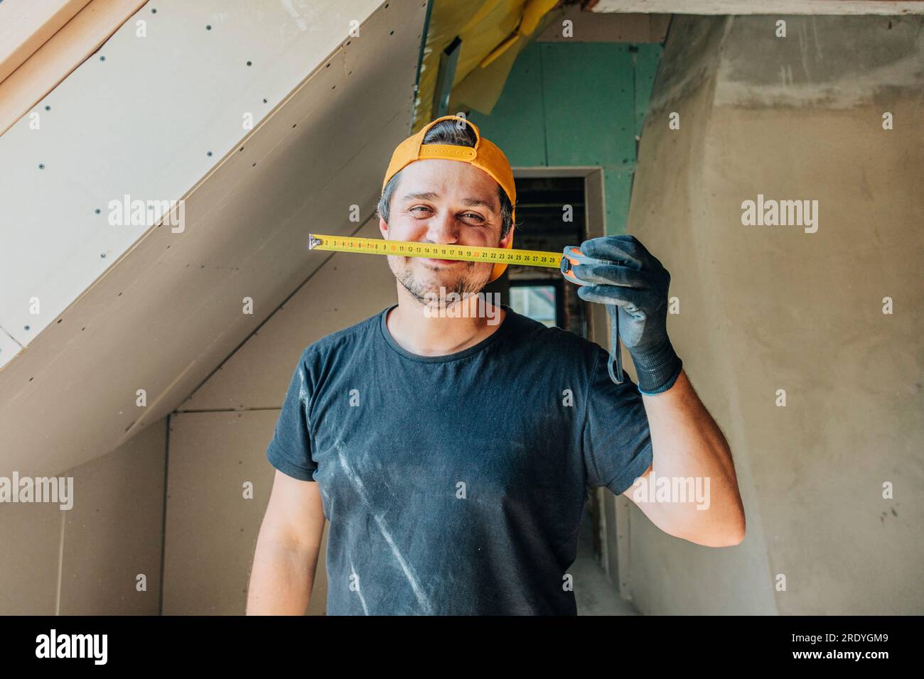 Happy man holding measuring tape in attic Stock Photo