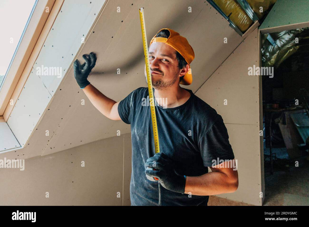 Man standing with measuring tape in attic Stock Photo