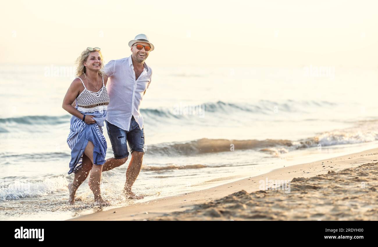 Happy Middle aged Couple In Love Walking In The Water On The Beach At 