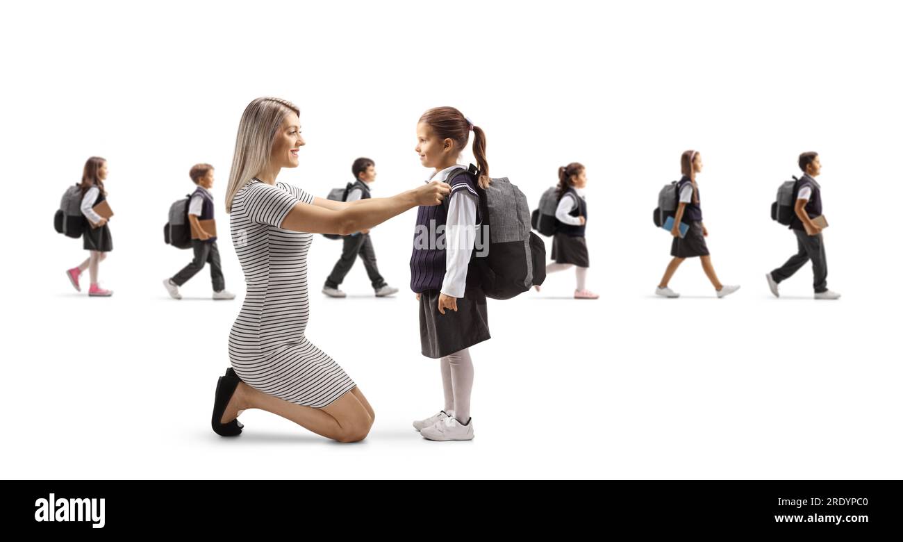 Mother helping daughter getting ready for school and other children walking in the back isolated on white background Stock Photo