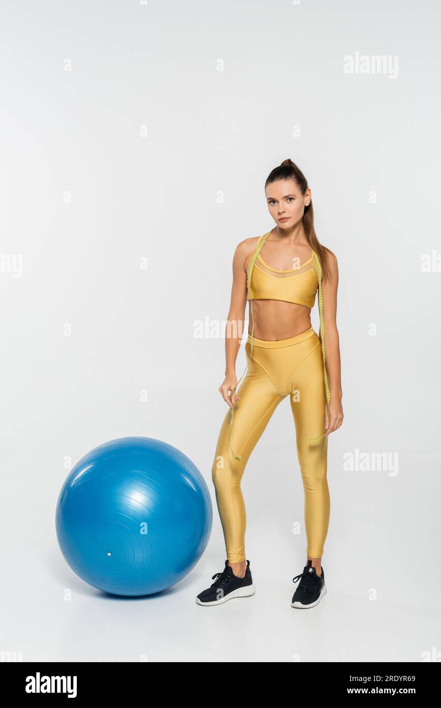 healthy habits, aerobics, woman in active wear and wireless headphones standing near fitness ball Stock Photo