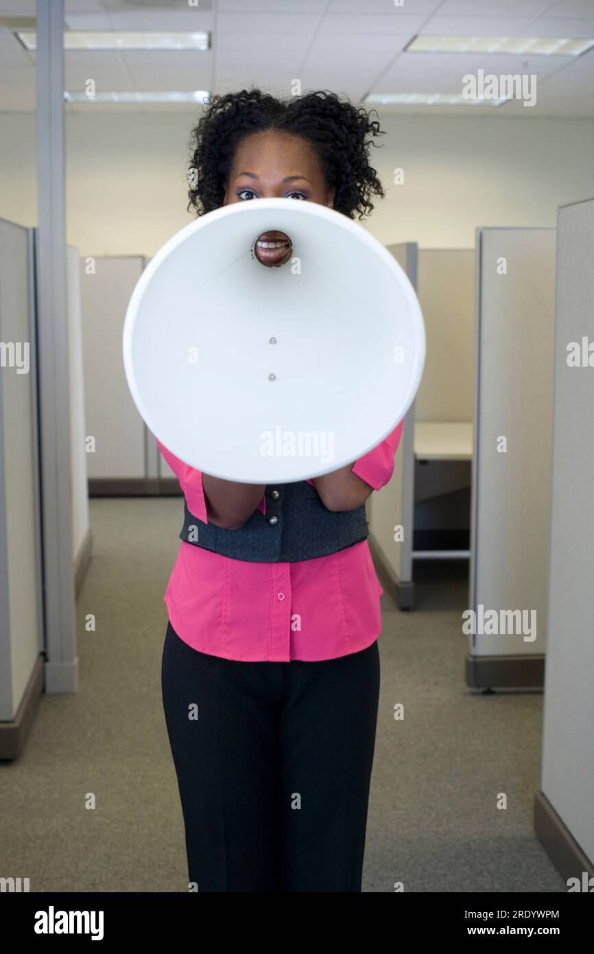 Woman with megaphone obscuring her face at work. Stock Photo