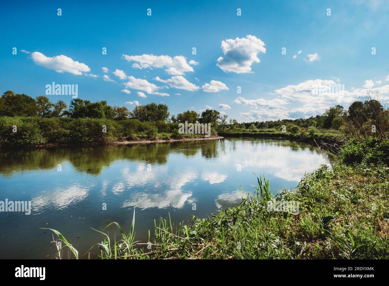 Sunny summer reflection landscape of river and sky in rural location Stock Photo