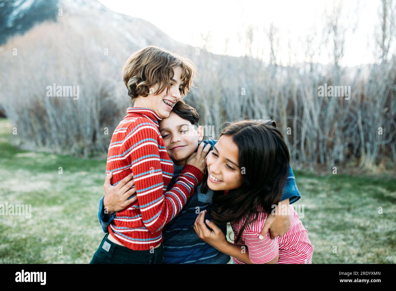 Little brother hugging two sisters one wants to get away Stock Photo