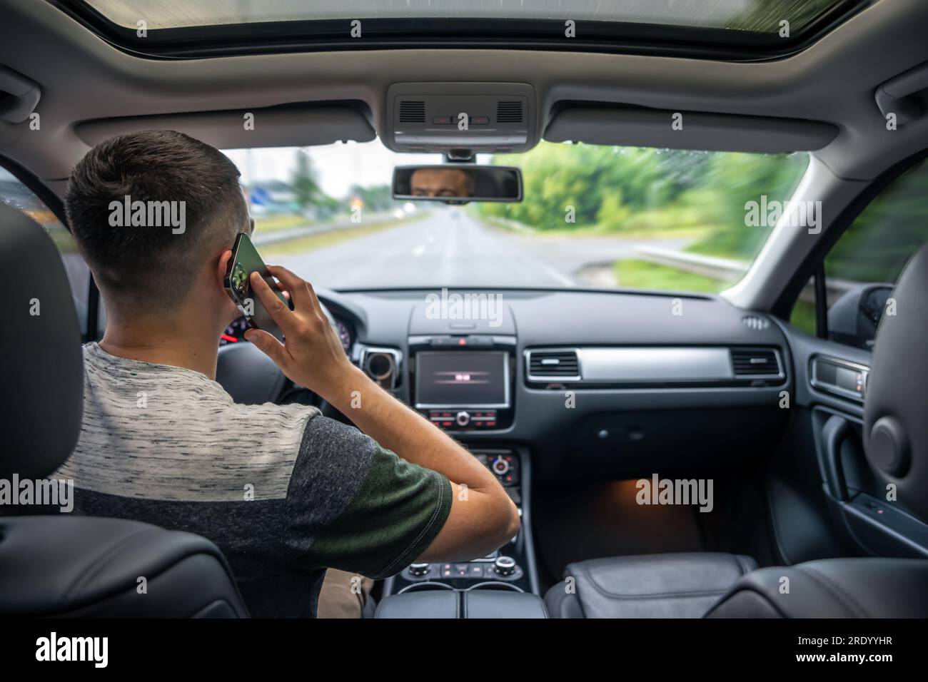 Businessman talking on cell phone while driving. Stock Photo