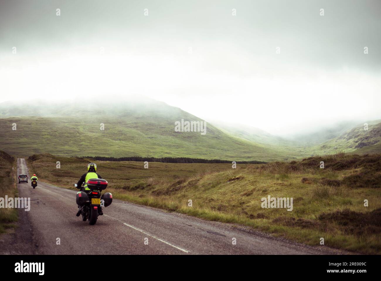 Motorbikes travel wet road through misty mountains in Scotland Stock Photo