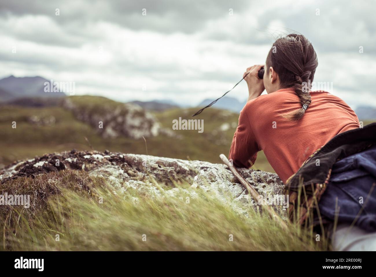 androgynous hiker with binoculars in mountains Stock Photo