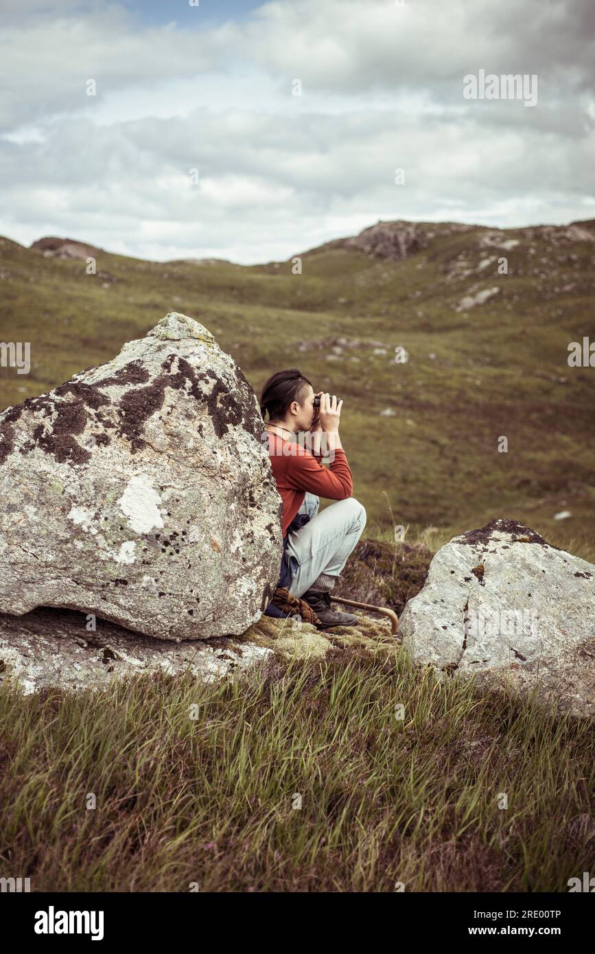 girl leans on rock with binoculars Stock Photo