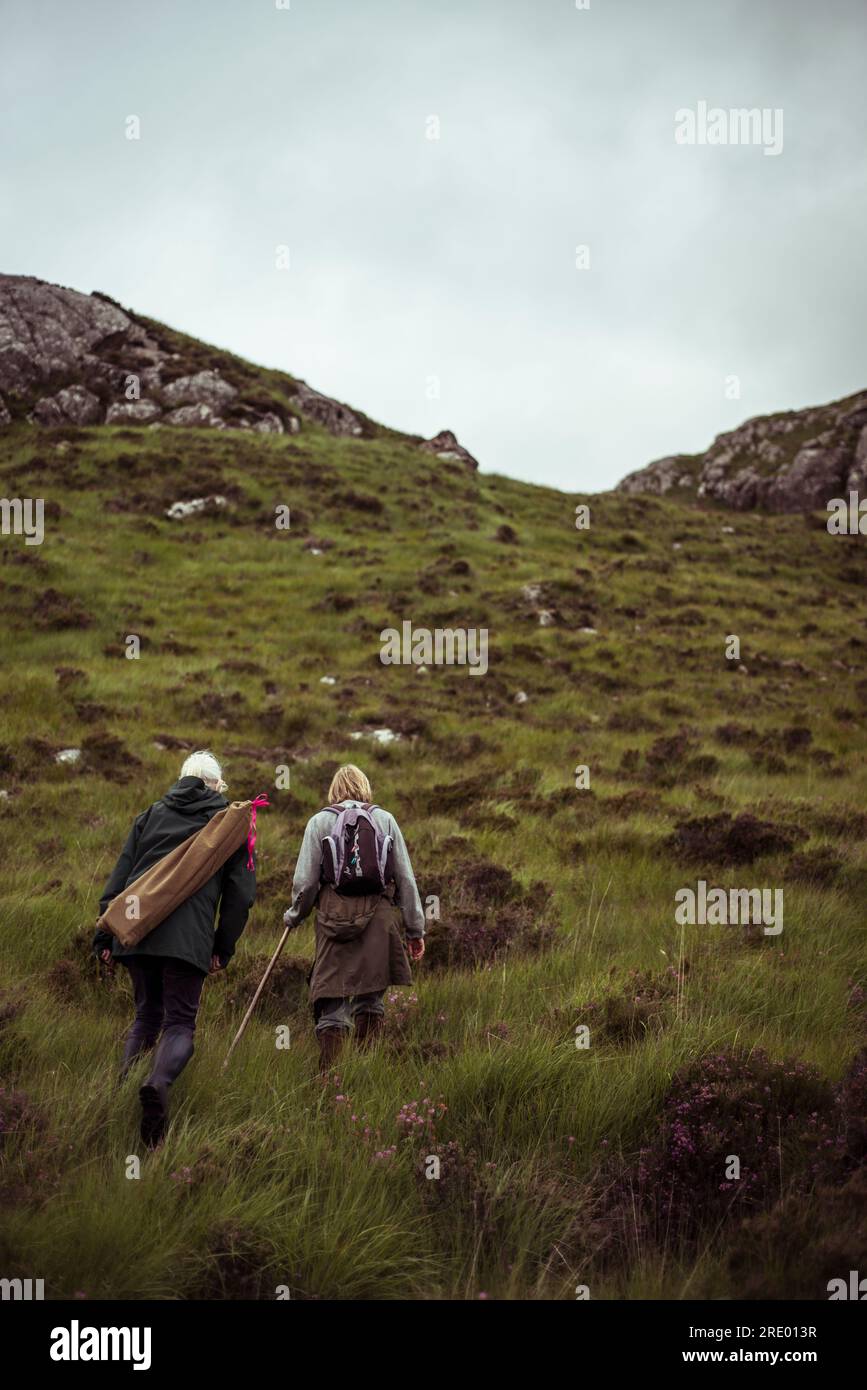 two retired women hike up remote mountain Stock Photo