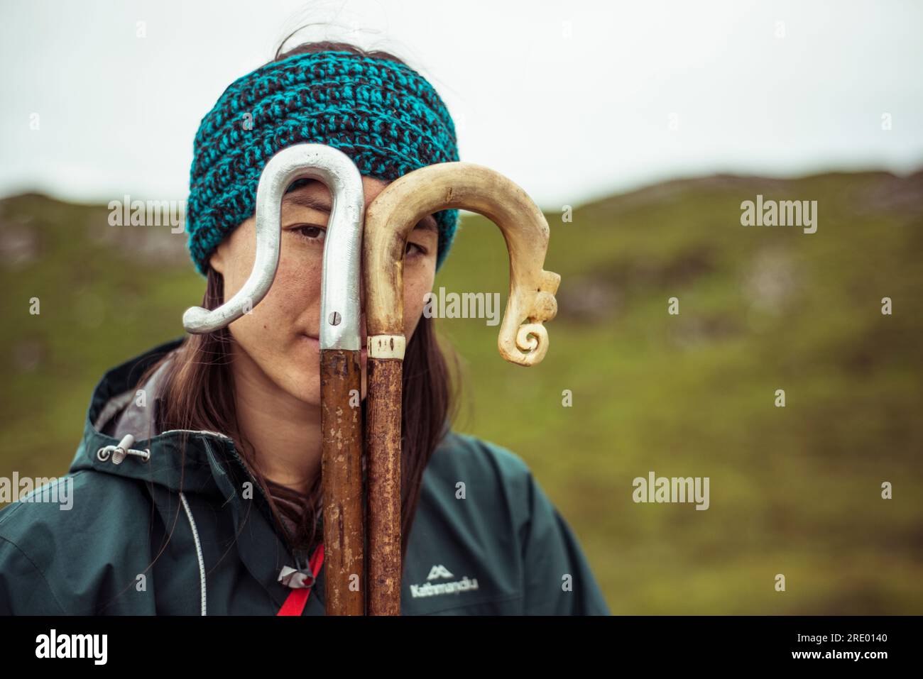 girl looks through hiking sticks in mountains Stock Photo