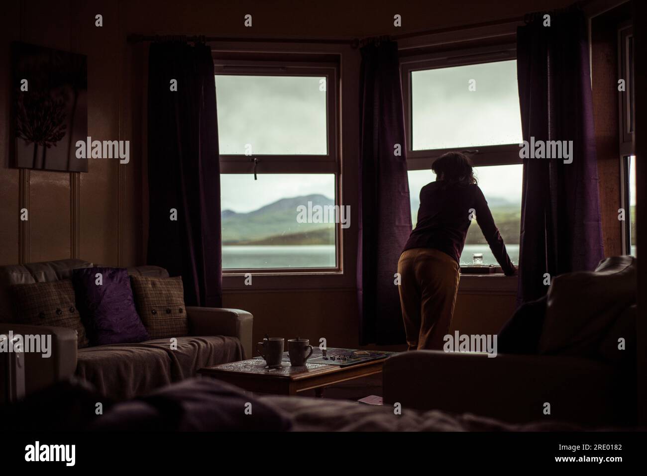 Silhouette of girl looking out window at mountain view Stock Photo