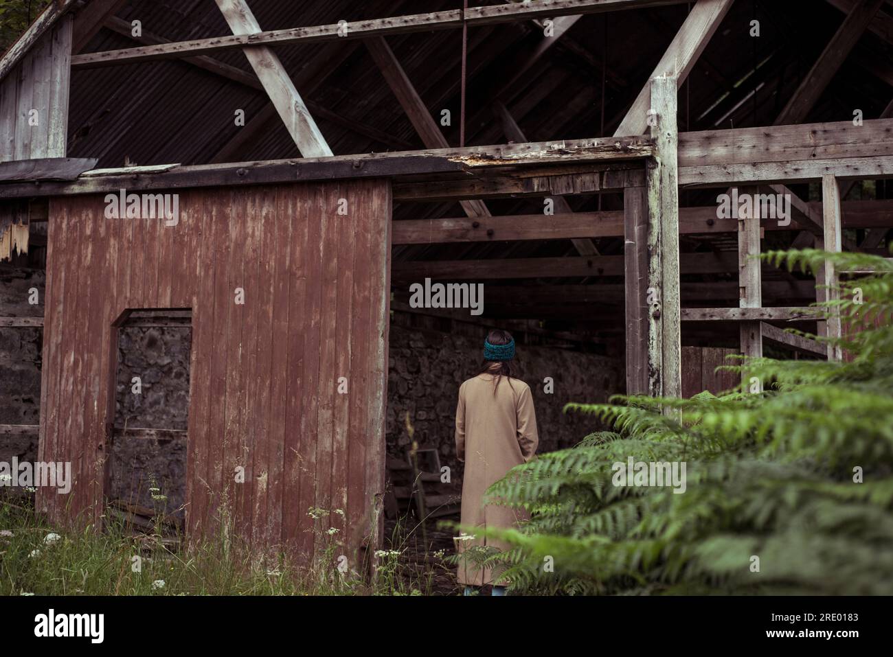 Person stands at door of old abandoned building overgrown Stock Photo