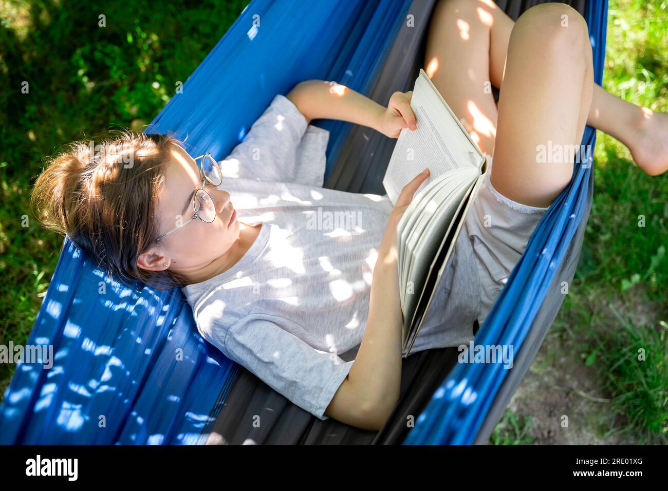 Cute girl reading a book in a hammock in the garden Stock Photo - Alamy