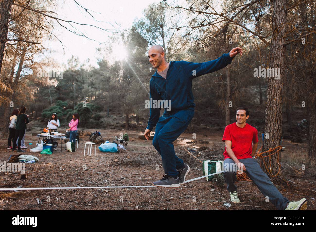 Man slacklining in pine tree forest in southern spain with friends Stock Photo