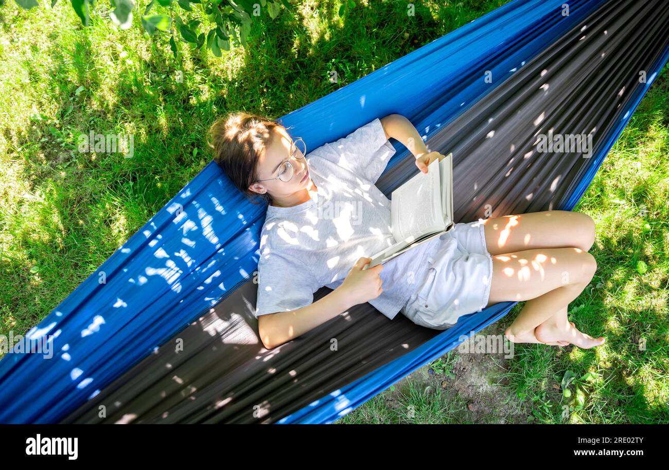 Cute girl reading a book in a hammock in the garden Stock Photo - Alamy