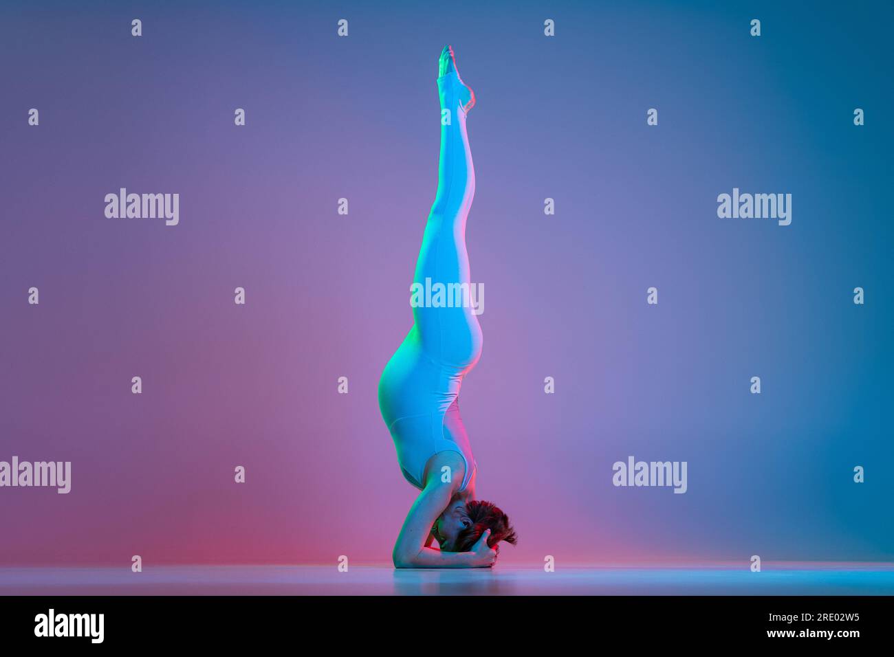 Pregnant woman doing headstand exercise in neon Stock Photo