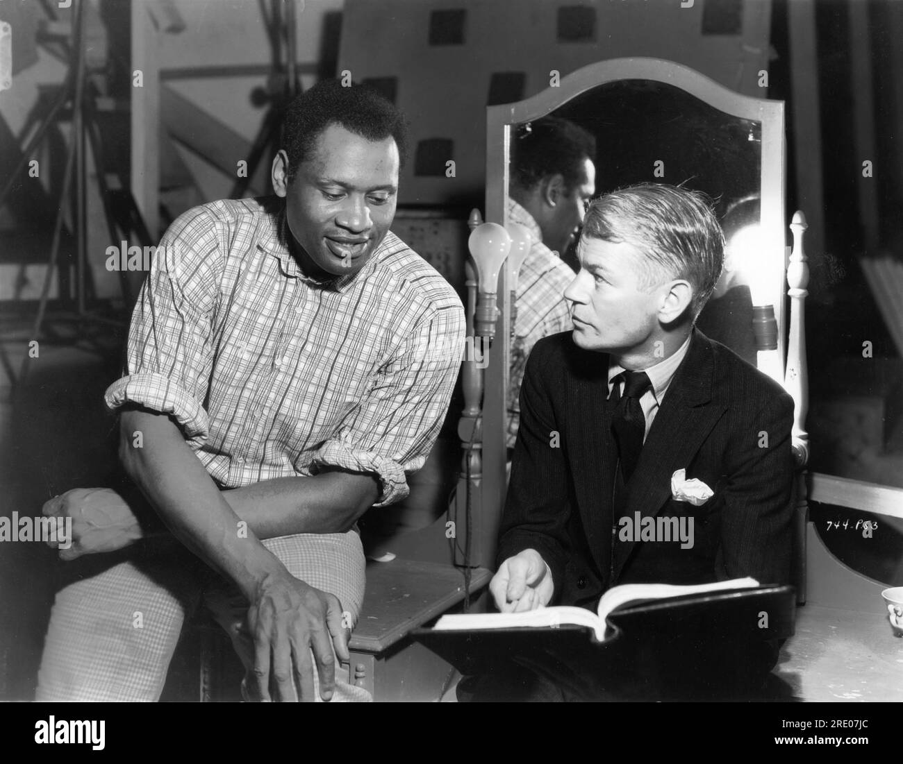 PAUL ROBESON and Director JAMES WHALE on set candid reading script during filming of SHOW BOAT 1936 director JAMES WHALE novel Edna Ferber music Jerome Kern lyrics Oscar Hammerstein II Universal Pictures Stock Photo