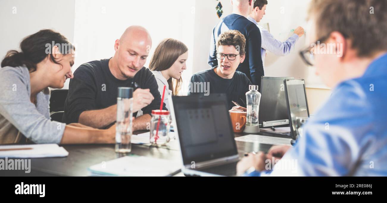 Startup business and entrepreneurship problem solving. Young AI programmers and IT software developers team brainstorming and programming on desktop computer in startup company share office space. Stock Photo