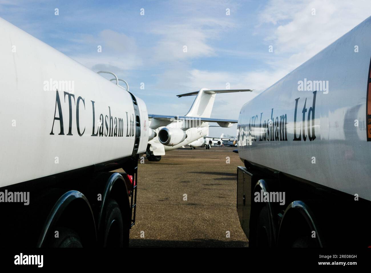 ATC Lasham Ltd, aircraft engineering company at London Southend Airport, Essex, UK. Aircraft framed by fuel tankers with branding Stock Photo