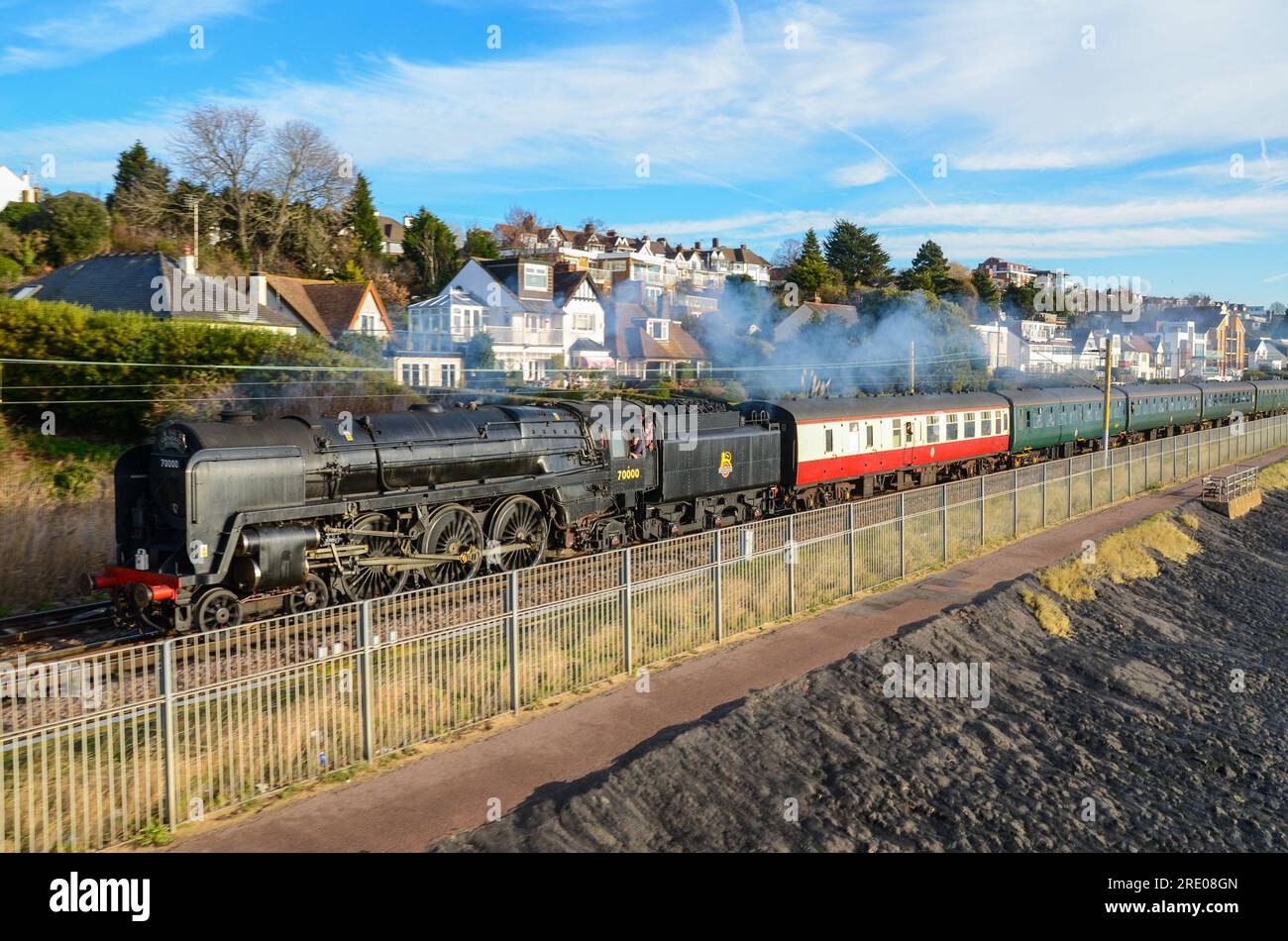 BR Britannia steam locomotive hauling a steam special from Southend, Essex passing Chalkwell beach on C2C line Thames Estuary. 70000 in black scheme Stock Photo
