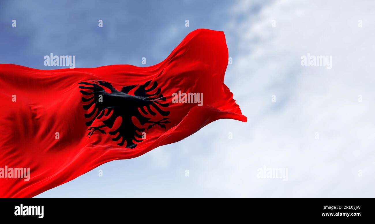 Albanian national flag waving in the wind on a clear day. Red flag with black two-headed eagle. 3d illustration render. Fluttering fabric. Stock Photo
