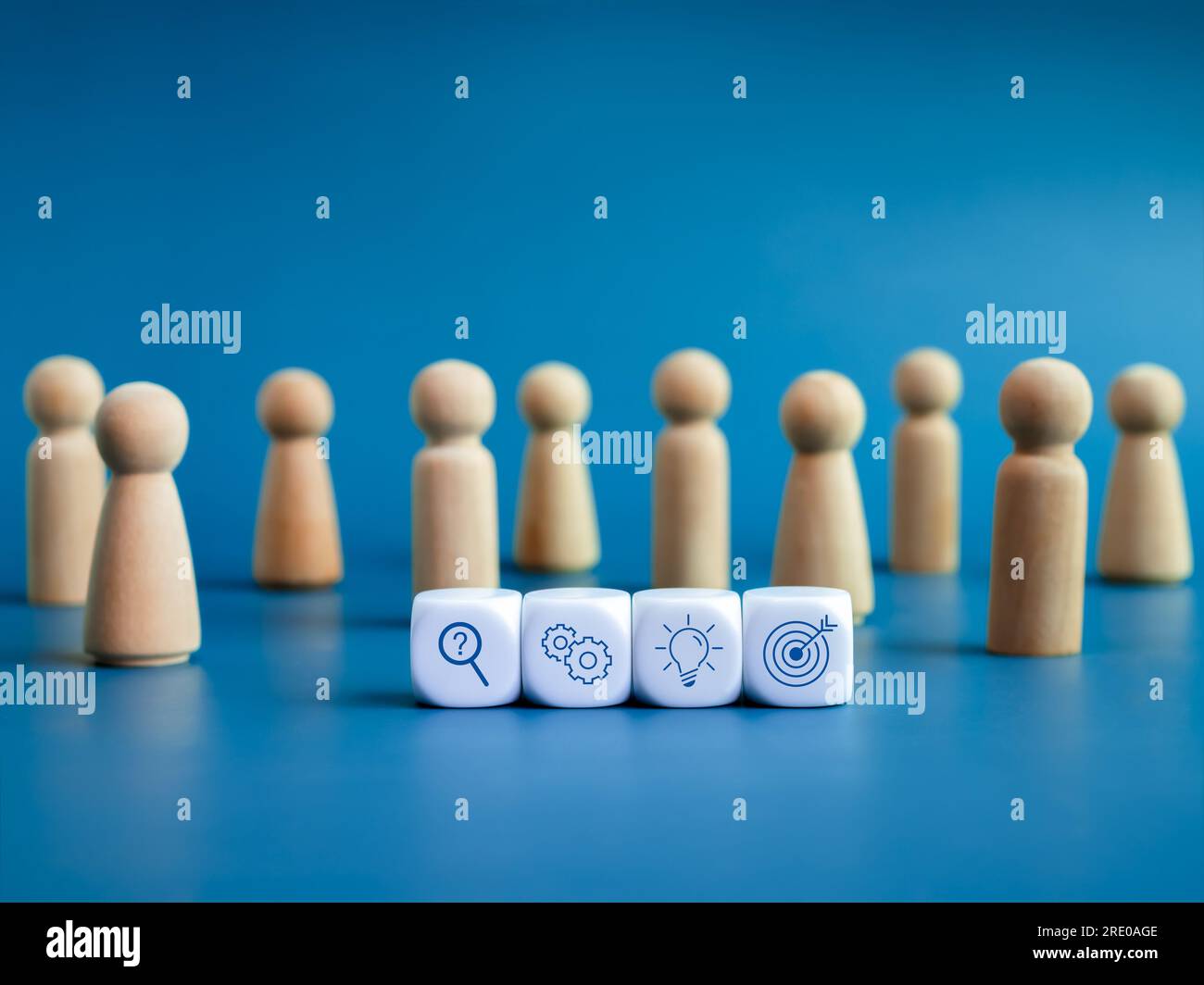 Business strategy and action plan icons on white cube blocks surrounded with wooden human figures on blue background. Team management, teamwork, busin Stock Photo